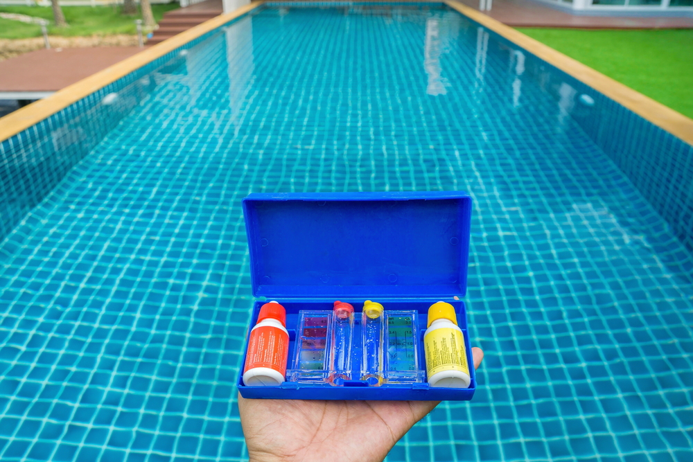 Individual holding a maintenance pool kit in front of pool